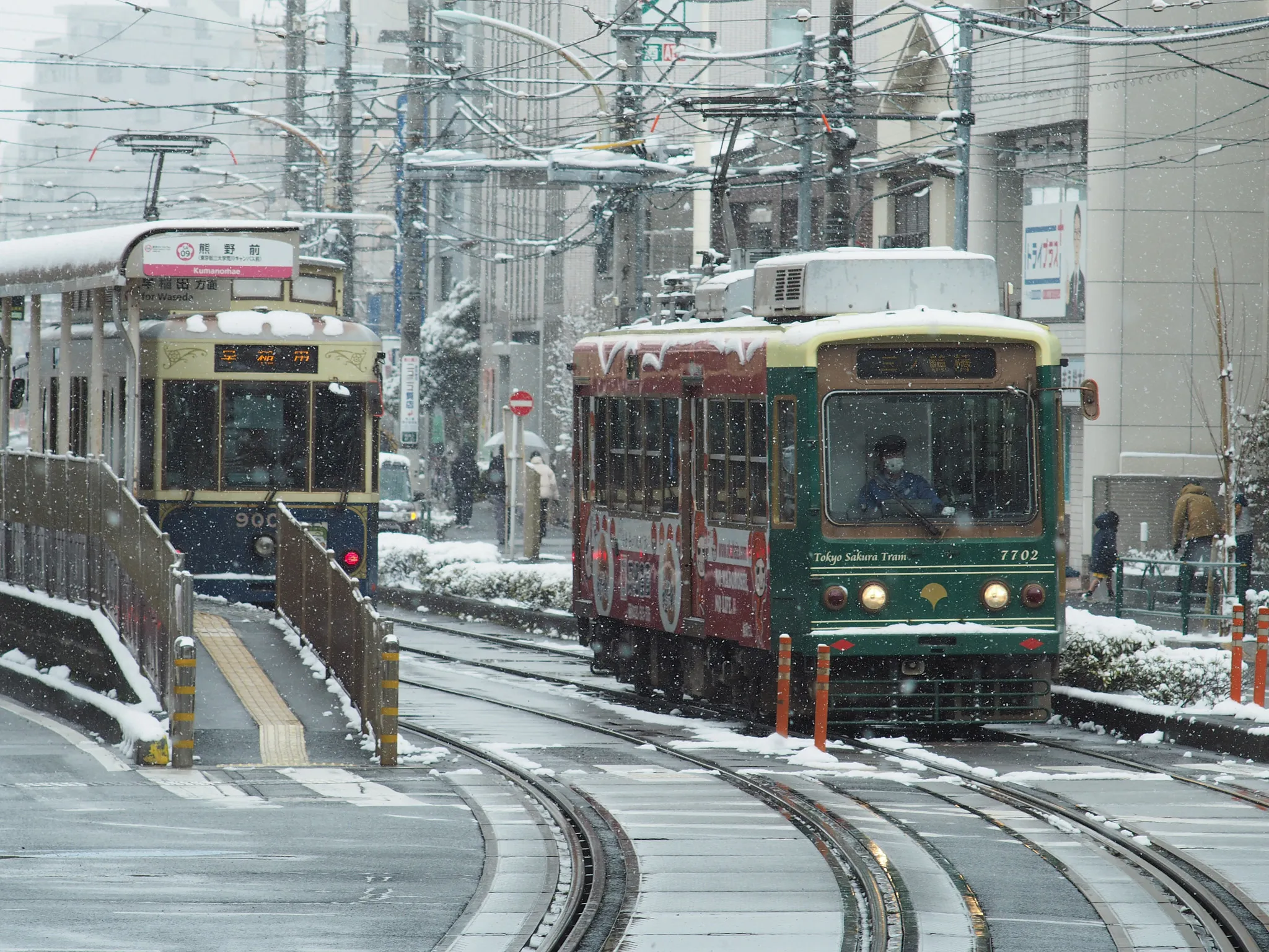 A Toden Arakawa Line 7700 series tram and a 9000 series tram meet at Kumanomae Station